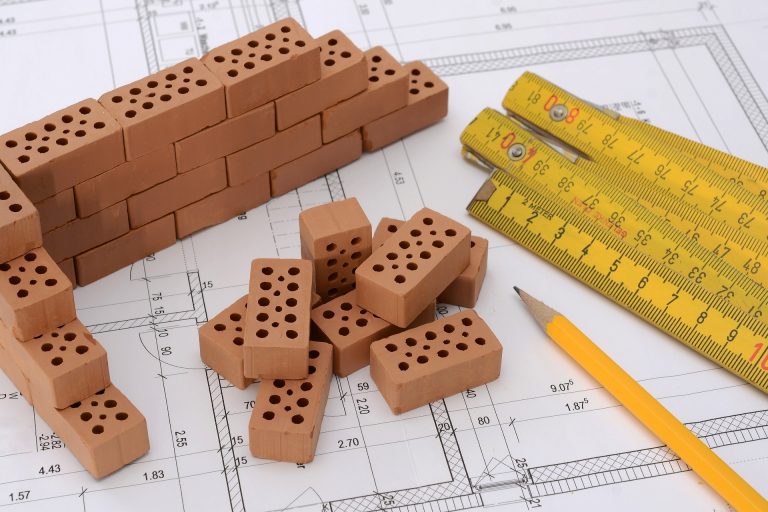 Bauskizze mit Miniaturbausteinen, einem Bleistift und einem Zollstock.